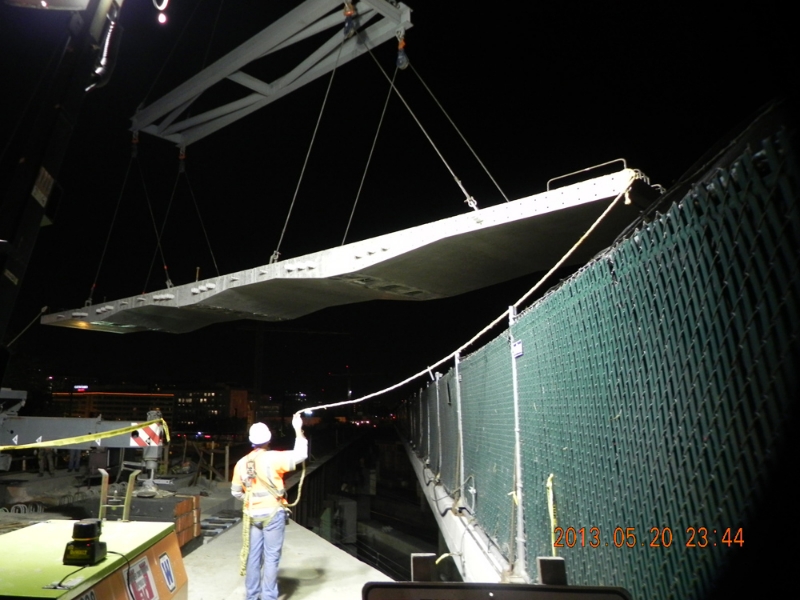 Installation of precast bridge deck panel over active rail lines during New York Avenue Bridge replacement in Washington, D.C.